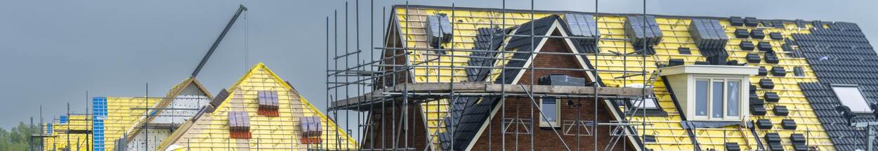huizen in aanbouw met diverse bouwmaterialen, vooral daken