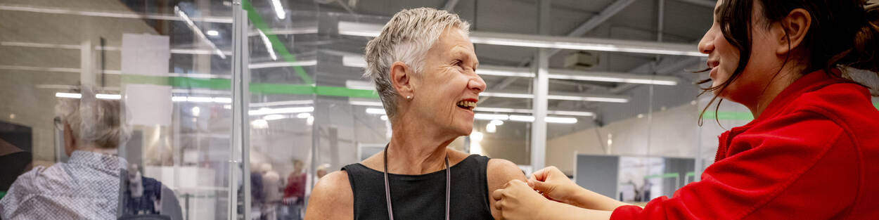 Verpleegkundige doet pleister op arm van vrouw na coronavaccinatie