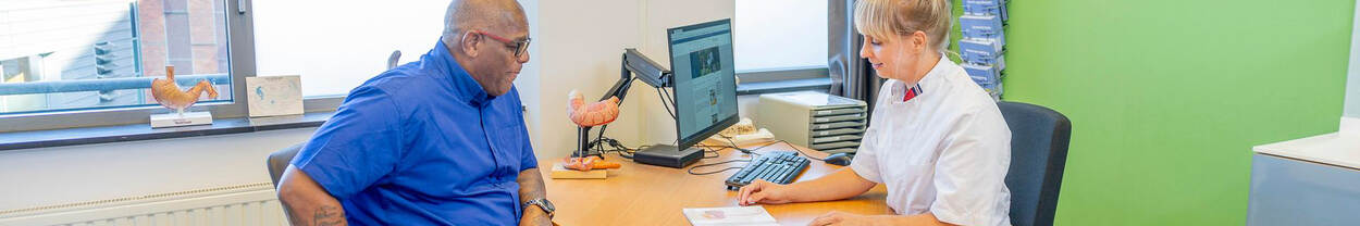 man zit aan tafel bij huisarts