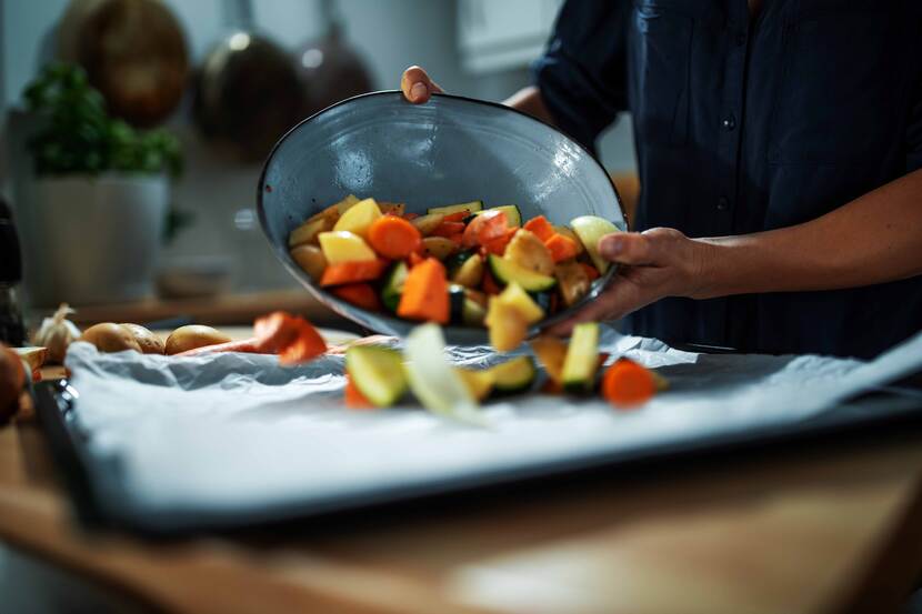 Man legt groenten op bakplaat