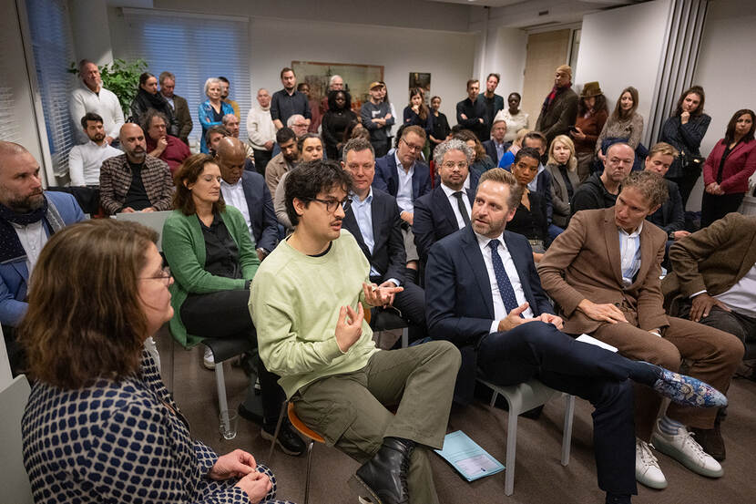 In een volle zaal is een man in het publiek aan het woord