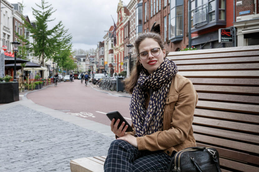 Vrouw met telefoon zit op een bankje